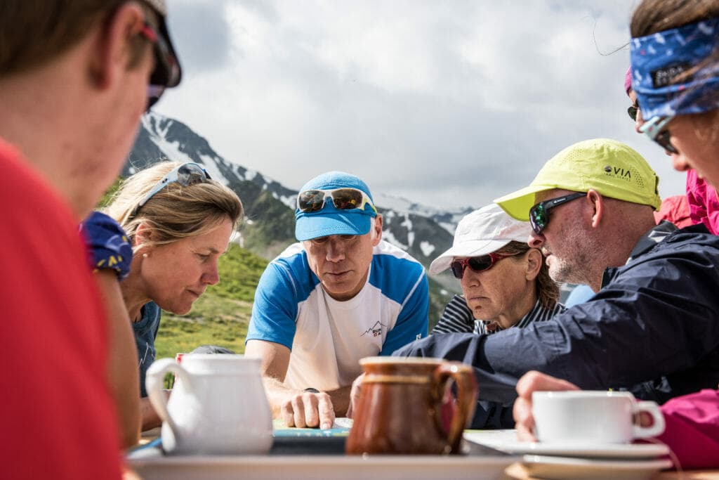 Guide Giles Ruck shows a map with the plan for the day on a table outside a hut. 