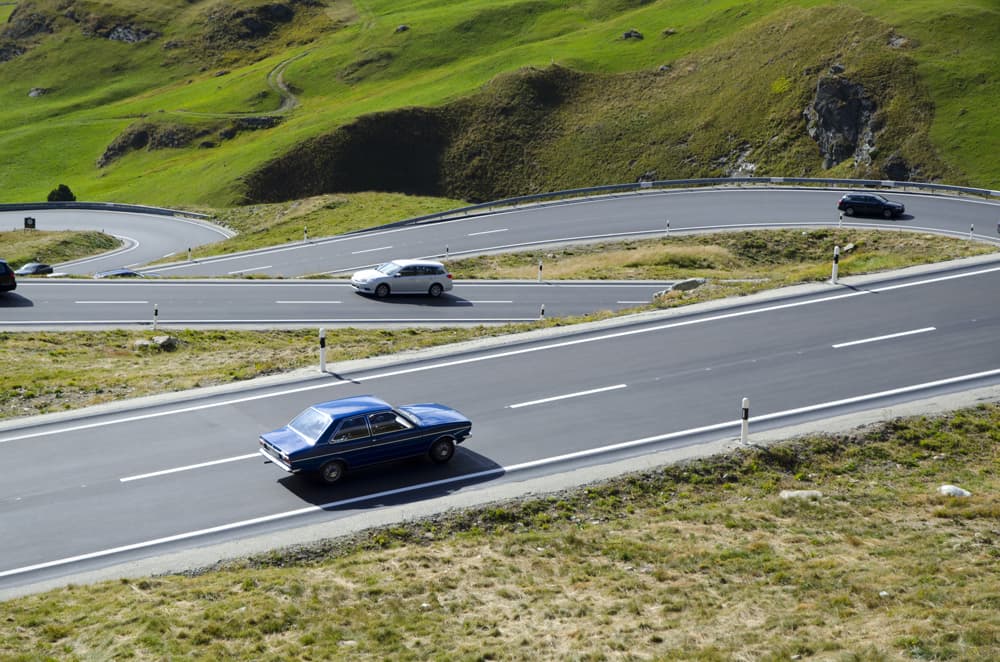 Cars on a curvy road surrounded by hills.