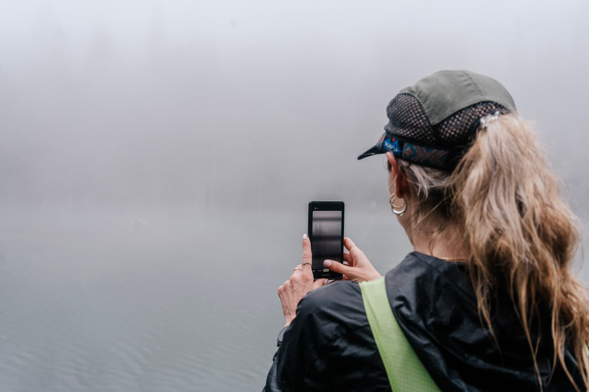 runner stops to take picture on phone of lake