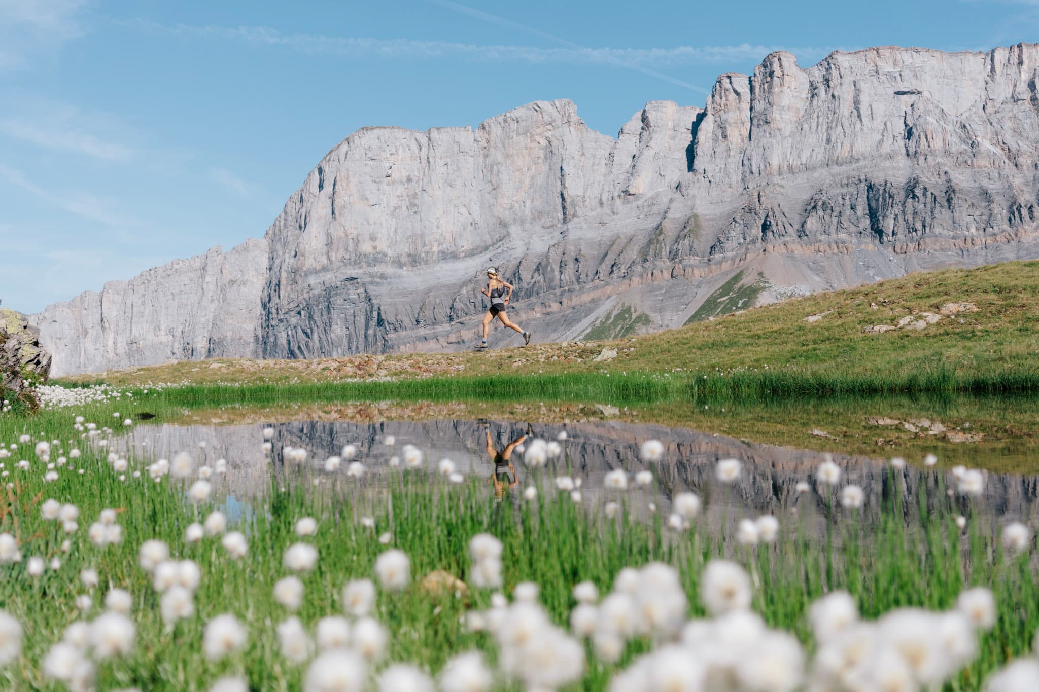 runner in distance with rocky cliff behind and lake in foreground
