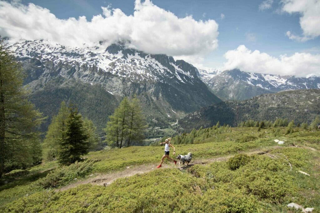 Mimmi Kotka in white shirt and with red shoes running on a single trail with dog