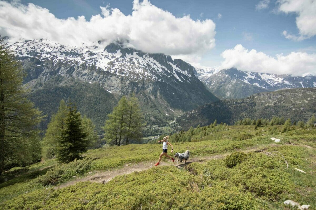 Mimmi Kotka in white shirt and with red shoes running on a single trail with dog