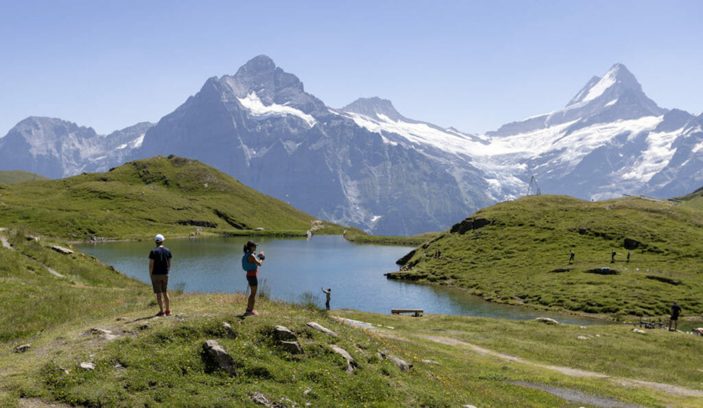 Trail runners taking in the views at Bachsee lake in front of the Eiger