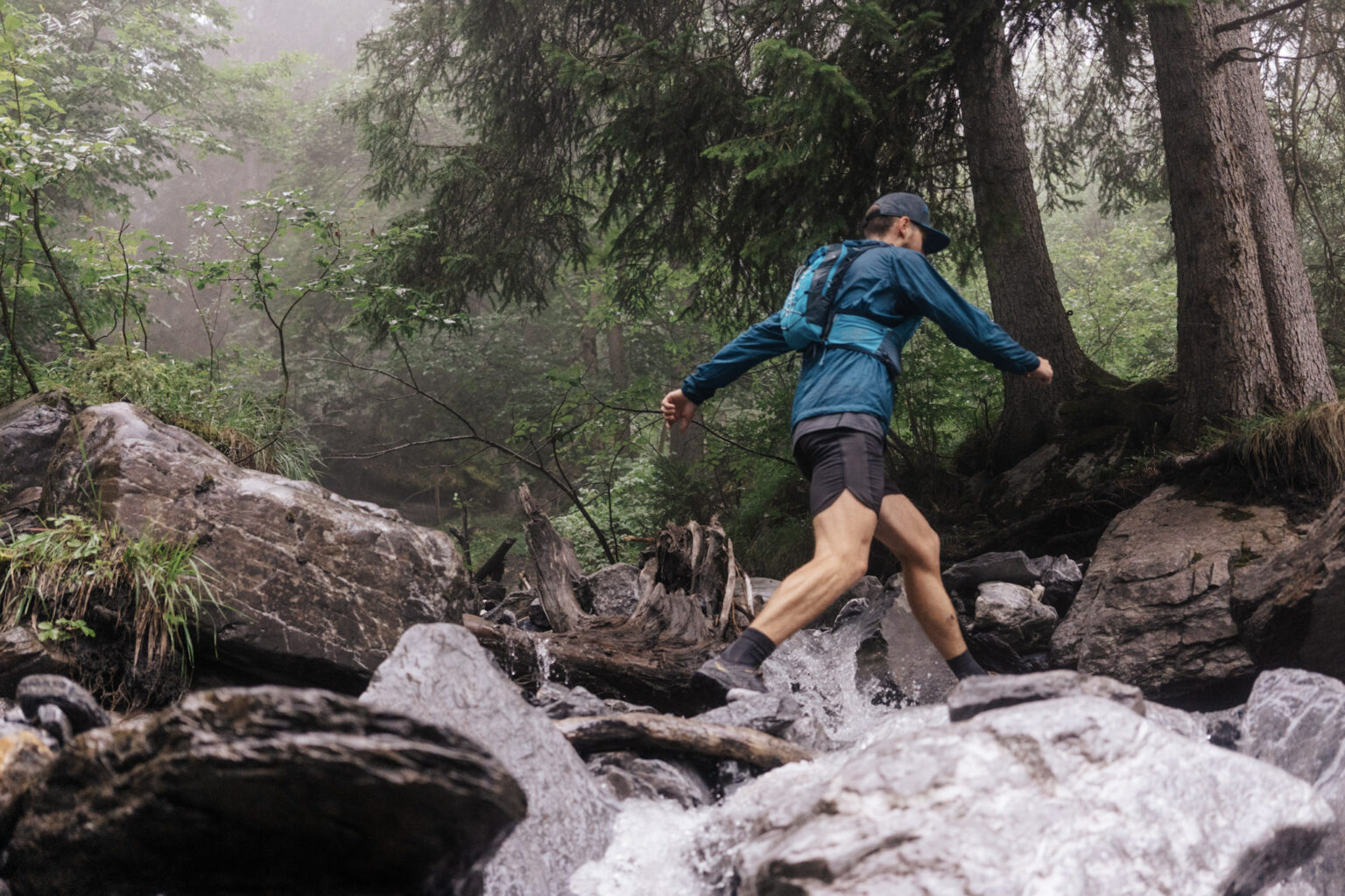 one runner crosses stream jumping between rocks