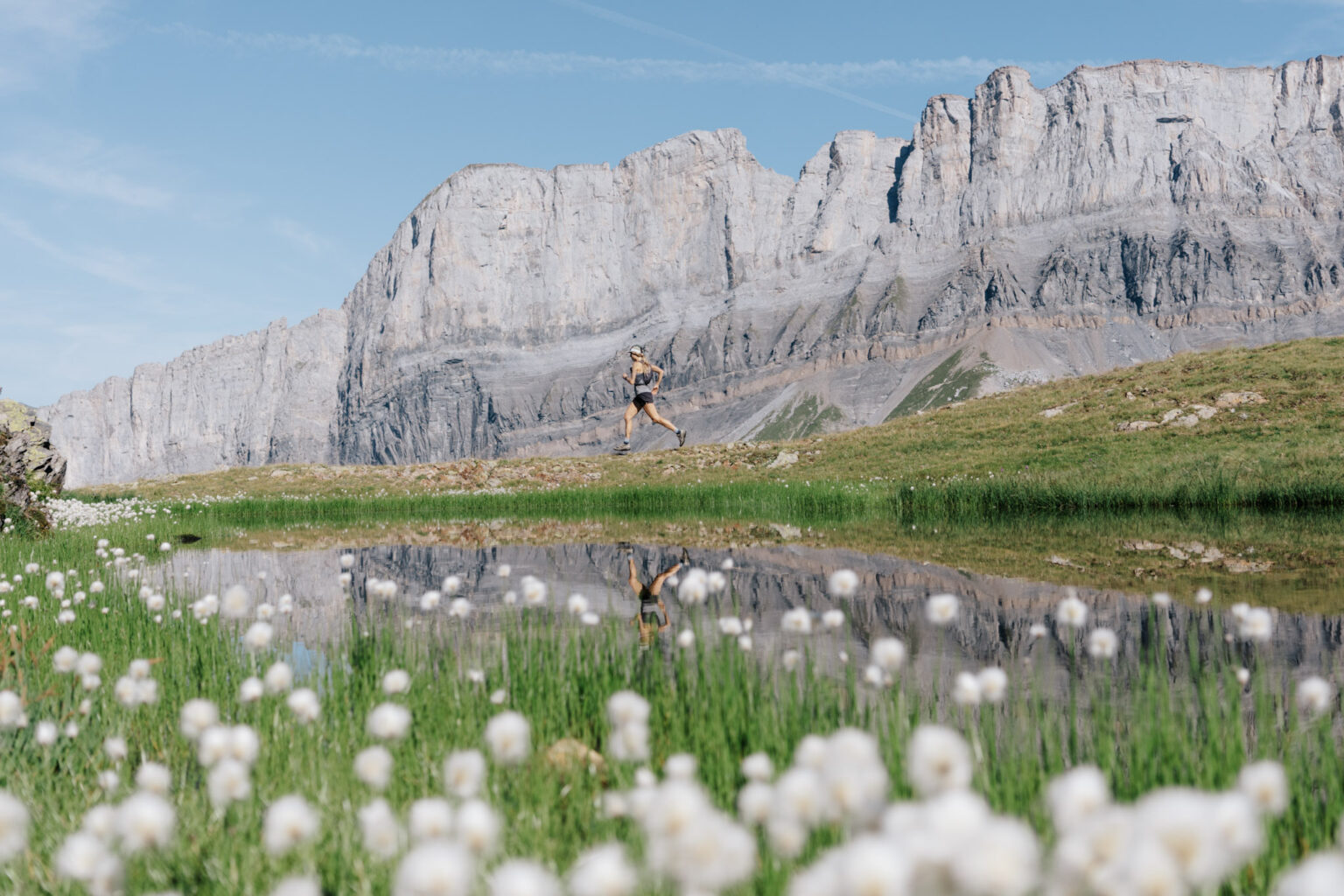 runner in distance with rocky cliff behind and lake in foreground