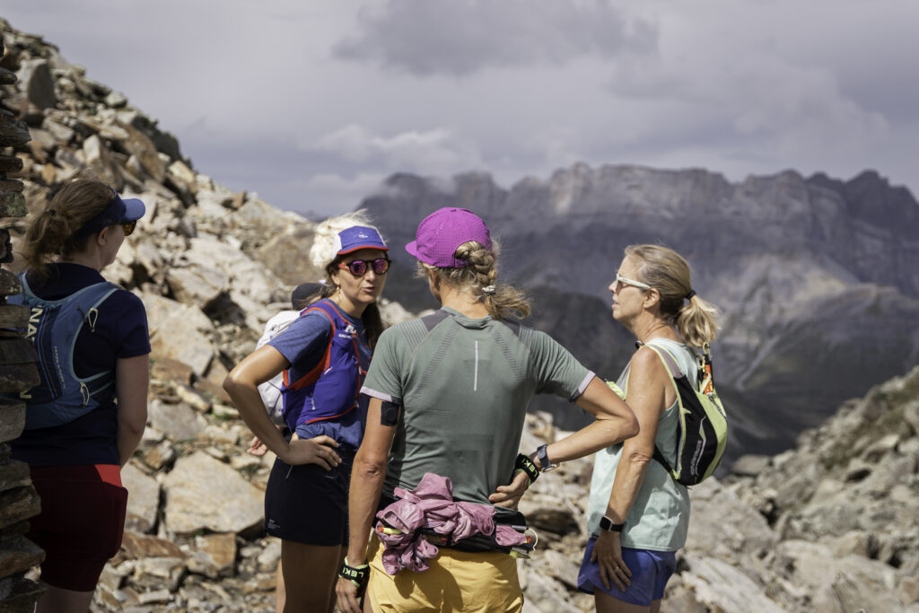 four women stopped to talk on a trail run in the Alps