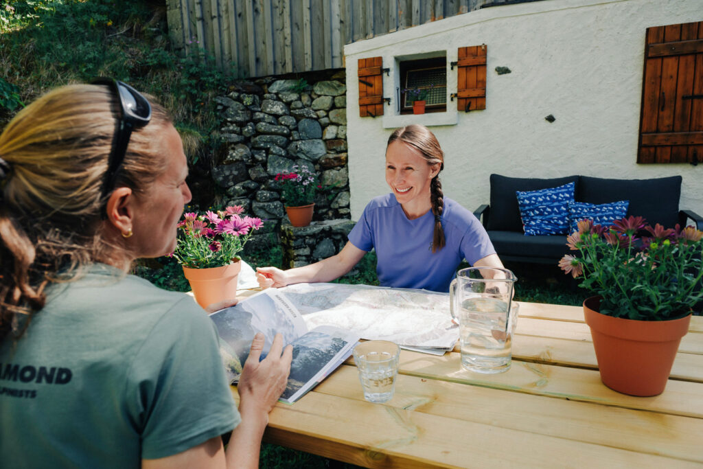 two women with books and maps outside a chalet