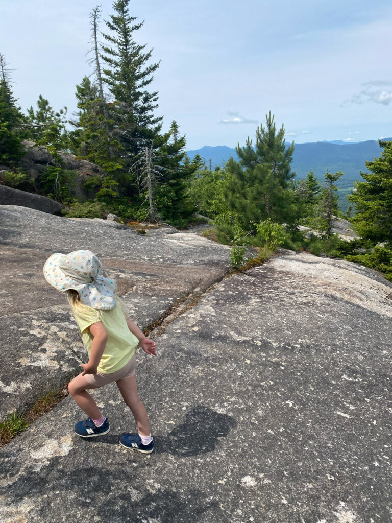 young girl in bonnet running on rock slabs