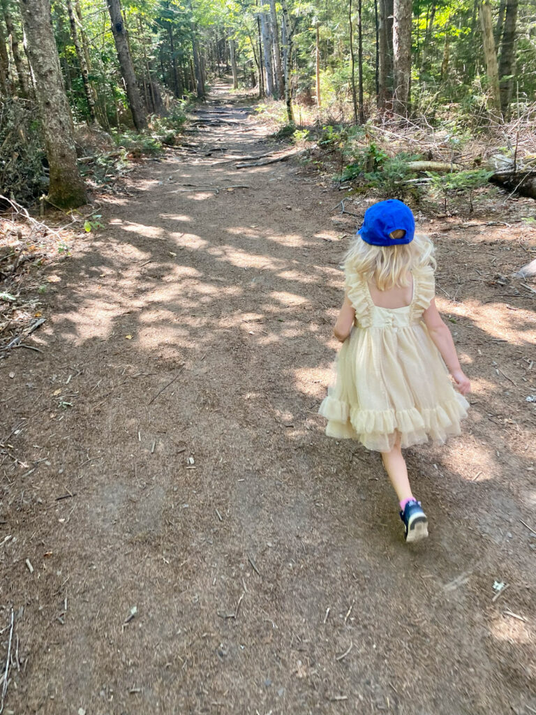 young girl in yellow dress and blue hat running