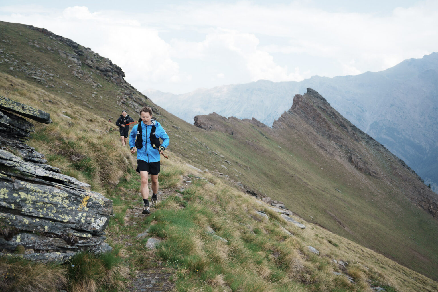 runner in blue jacket on a ridge trail