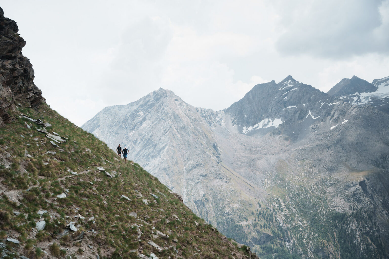 two runner silhouettes below big peaks in Italy