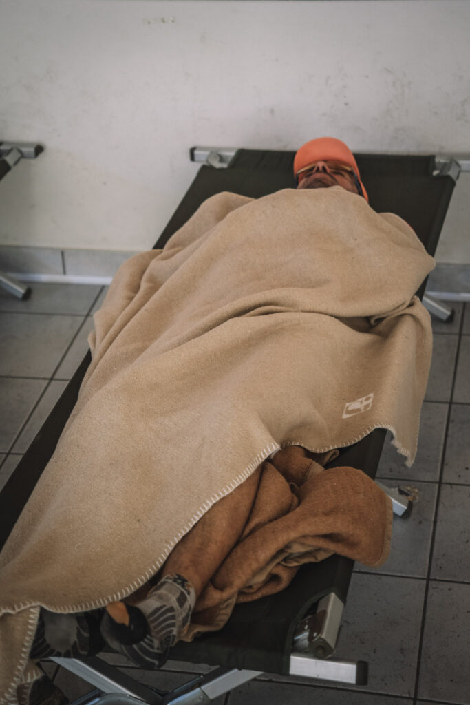 a man in a cot covered with a tan blanket during Tor